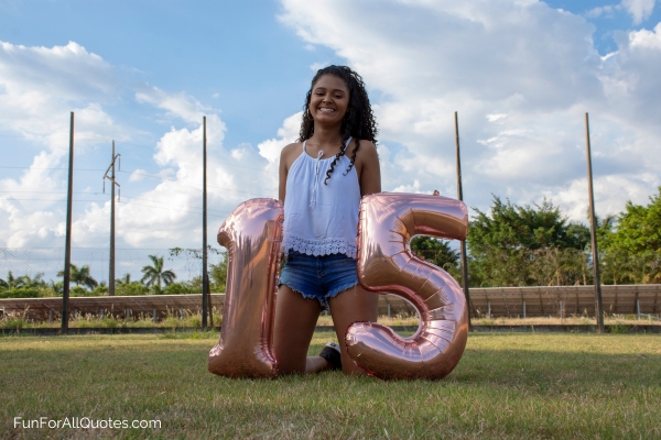 15-year-old girl kneeling on grass holding 1 and 5 balloons