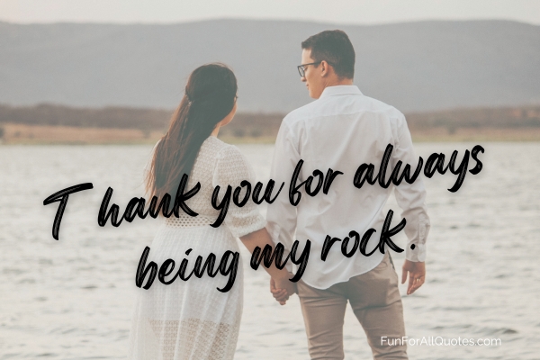 Couple holding hands facing body of water, with quote overlay